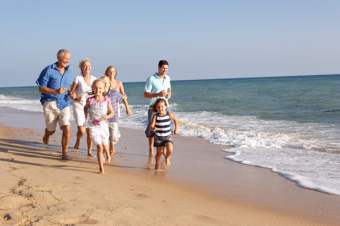 Multigenerational family running on beach